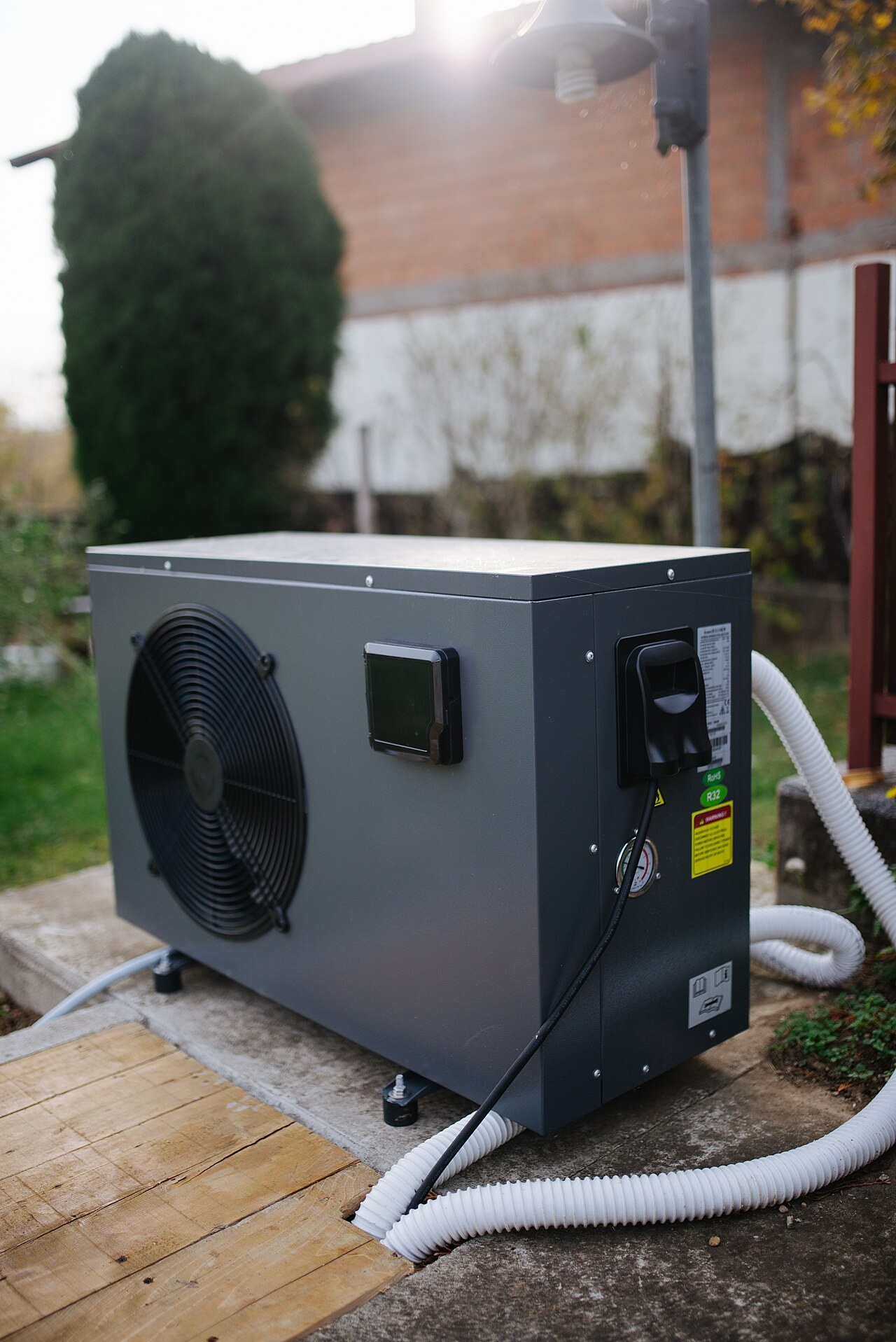 Residential outdoor heat pump on a pad beside a house