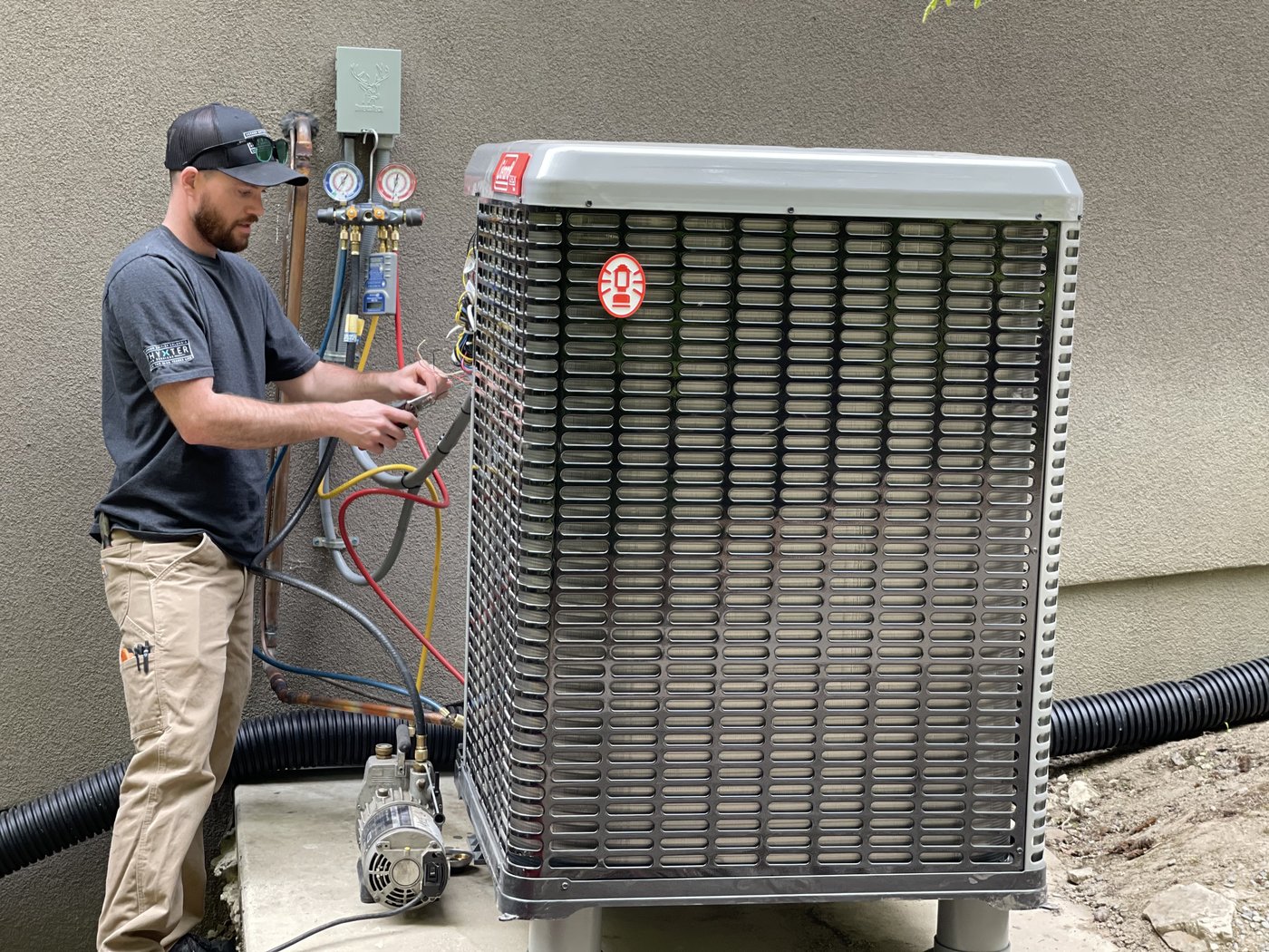 Technician servicing a residential outdoor AC condenser on a pad