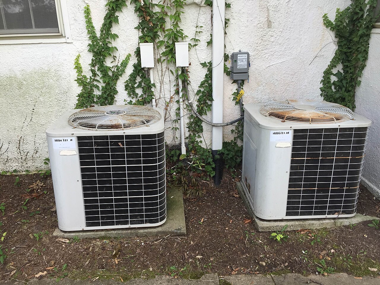 Two residential outdoor AC condensers on concrete pads